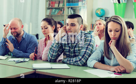 Portrait of bored adult students sitting at lesson in classroom Stock Photo