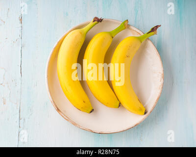 Bananas in a white dish on green pastel background. Nutrition concept Stock Photo