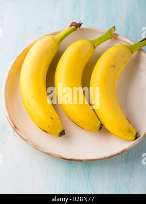 Bananas in a white dish on green pastel background. Nutrition concept Stock Photo