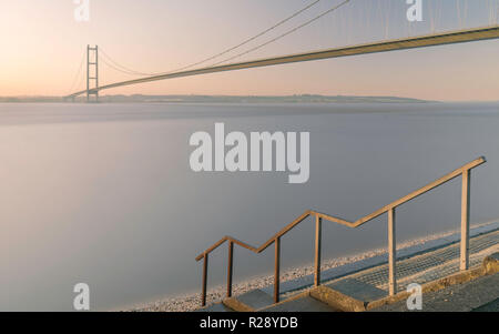 Humber bridge over the estuary as dawn breaks at high tide in autumn, Yorkshire, UK. morning in autumn, Yorkshire, UK. Stock Photo