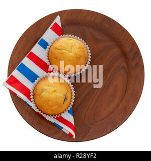 Homemade fruit muffins, cupcakes on red white and blue serviette, napkin on plate, isolated on white. Two small home baked cakes, overhead flat lay. Stock Photo