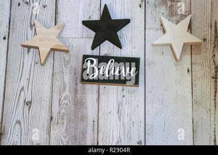 Rustic Christmas holiday flatlay with wood stars, and a black and white Believel word on wood background Stock Photo