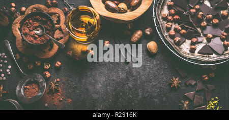 Chocolate background with various nuts, spices, cacao powder and spirits, top view. Homemade confectionery with pralines and truffles ingredients. Bro Stock Photo