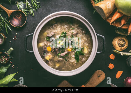 Top view of  beef and cabbage soup or stew in cast iron cooking pot on dark background with ingredients and wooden spoon, top view. Healthy clean low- Stock Photo