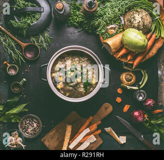 Beef and cabbage soup or stew in cast iron cooking pot on dark background with low carb vegetables, spices ingredients and wooden spoon, top view. Hea Stock Photo