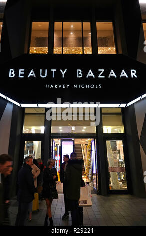 People in silhouette walking past a Harvey Nichols Beauty Bazaar store in Liverpool One shopping complex at night. Liverpool UK. November 2018. Stock Photo