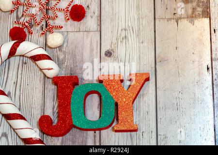 Christmas holiday flatlay with sparkle glittery Joy word in red plaid, decorative candy cane and a twine snowflake. Useful for rustic backgrounds Stock Photo