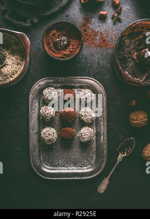 Healthy vegan homemade truffles making. Coated in cacao powder and almond flour truffle balls on dark rustic kitchen table background, top view. Stock Photo
