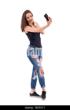 Relaxed young beautiful happy woman having fun with mobile phone camera. Full body isolated on white background. Stock Photo