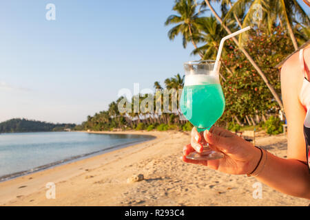 Woman holding Blue Cocktail at Paradise Beach Stock Photo