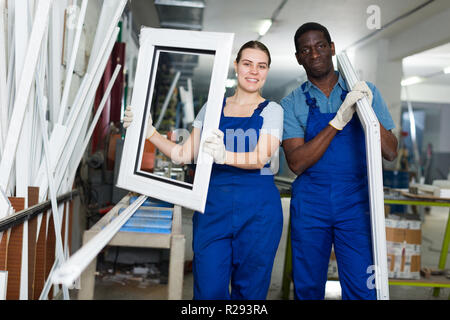 Two masters are working with window frame in the window workshop. Stock Photo