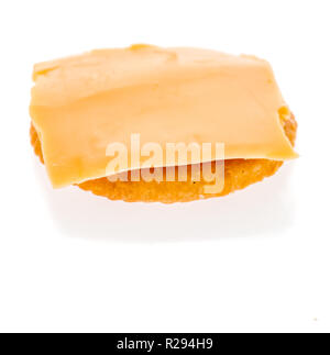 A cracker with a piece of sliced cheese placed on it on an isolated background Stock Photo