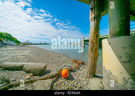 Waimea Estuary with old chain and orange buoy lying under wharf above low tide at Mapua South Island New Zealand. Stock Photo