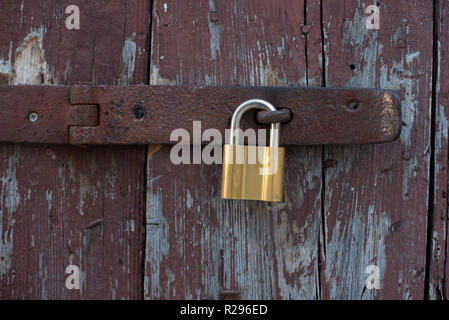 Old wooden doors locked with metal yellow lock. New yellow lock on old brown doors. Stock Photo
