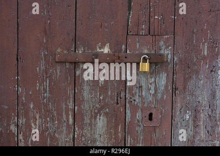 Old wooden doors locked with metal yellow lock. New yellow lock on old brown doors. Stock Photo