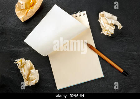 No Ideas. A spiral note pad with a blank sheet of paper and torn out crumpled pages, shot from above on a dark background with a sharp graphite pencil Stock Photo