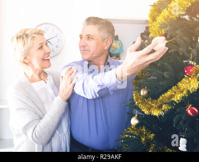 Friends are hang up New Year's toys on a fir-tree before Christmas holiday. Stock Photo