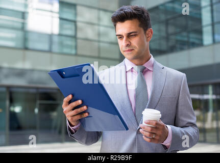 Businessman holding folder with documents and attentively reading Stock Photo