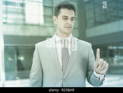 Businessman pressing imaginary button on large plant background Stock Photo