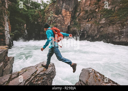 Running man travel adventure active vacations healthy lifestyle endurance extreme sport concept backpacker jumping on cliff above canyon river Stock Photo