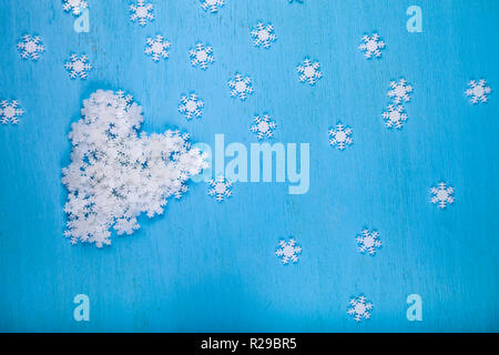Christmas snowflakes on blue wooden background. Heart of white snowflakes. Stock Photo