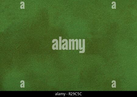 Dark green matte background of suede fabric, closeup. Velvet texture of seamless emerald leather. Felt material macro. Stock Photo
