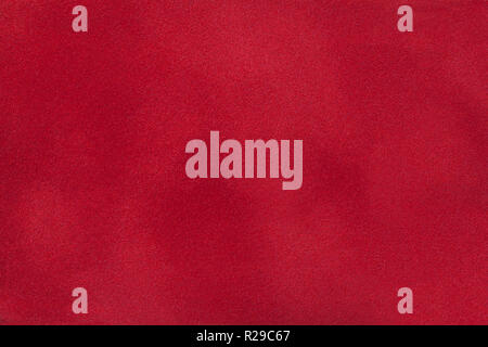 Dark red matte background of suede fabric, closeup. Velvet texture of seamless wine leather. Felt material macro. Stock Photo