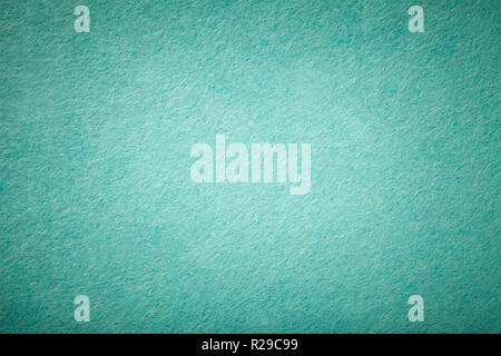Light turquoise matte background of suede fabric, closeup. Velvet texture of seamless green woolen felt with vignette. Stock Photo