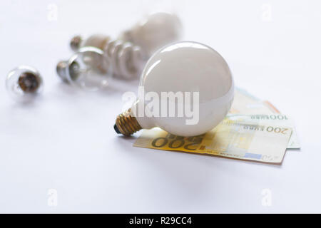 Big white Light Bulb on european cash banknotes. Different kind of bulbs. Coins. Stock Photo