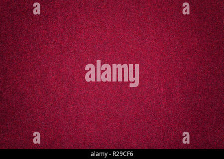 Dark red matte background of suede fabric, closeup. Velvet texture of seamless wine woolen felt with vignette. Stock Photo