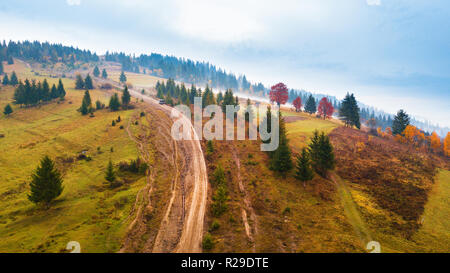Off-road car climbing on a mountain extreme rural dirt road. Muddy hillside in autumn rainy season Stock Photo