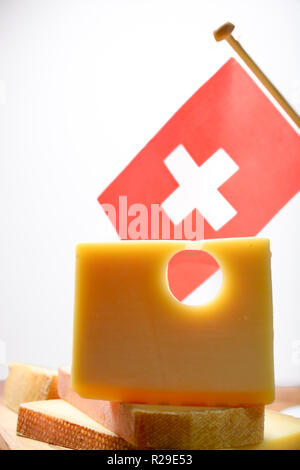 Block of Swiss Emmental or Emmentaler medium-hard cheese with round holes made from cow milk in Canton Bern with flaf of Switzerland Stock Photo