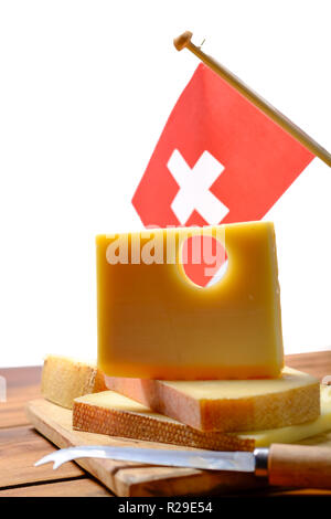 Block of Swiss Emmental or Emmentaler medium-hard cheese with round holes made from cow milk in Canton Bern with flaf of Switzerland Stock Photo