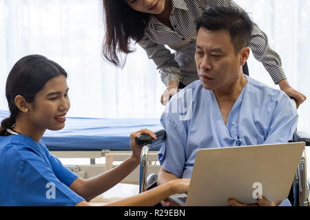 Physical therapist explain treatment method to senior patient and relative using notebook Stock Photo