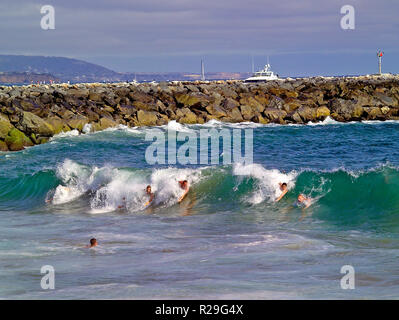 Bodysurfers ride Pacific Ocean surf at The Wedge on the Balboa Peninsula, where extreme waves form next to the rock jetty that protects the boat channel entrance to Newport Harbor at Newport Beach in Orange County, Southern California, USA. Stock Photo