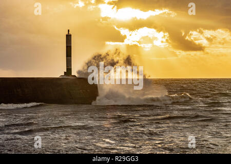 The sun setting over Aberystwyth stone jetty during stormy weather. Stock Photo