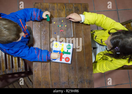 Little brothers playing Parchis over wooden vintage table. Overhead view. Traditional board game Stock Photo