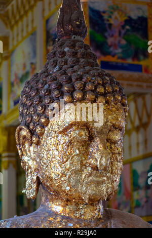 The portrait of Buddha gilded of petals inside Buddhist temple in Thailand. Golden foil on Buddha statue. Stock Photo