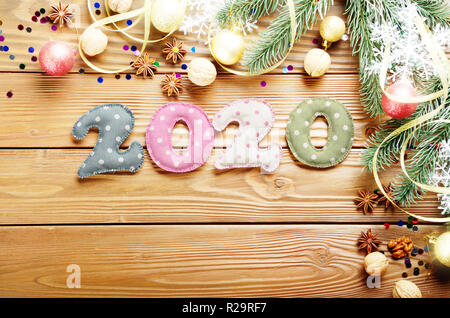 Colorful stitched digits 2020 of polka-dot fabric with Christmas decorations flat lied on wooden background Stock Photo