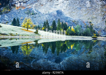 Peaceful autumn view on Obersee lake in Swiss Alps. Frosty grass and mountains reflections in clear water. Nafels village, Switzerland.