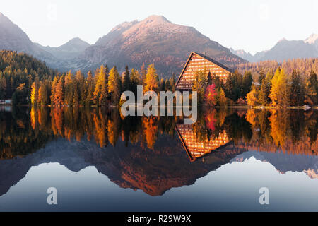 Picturesque autumn view of lake Strbske pleso in High Tatras National Park, Slovakia. Clear water with reflections of orange larch and high mountains
