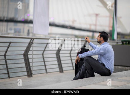 arab businessman with his suitcase in a city, resting on stairs Stock Photo