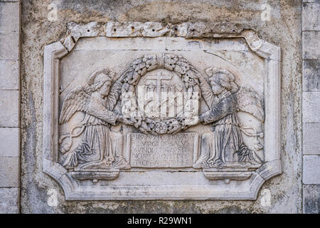 Old plaque depicting angels holding round wreath on the wall of a Old Town church in Dubrovnik, Croatia Stock Photo