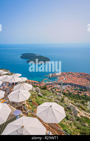 Umbrellas providing shadow for restaurant customers on top of a Srd Hill with the view of the old city of Dubrovnik, on the UNESCO list of World herit Stock Photo