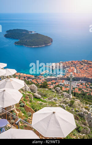 Umbrellas providing shadow for restaurant customers on top of a Srd Hill with the view of the old city of Dubrovnik, on the UNESCO list of World herit Stock Photo