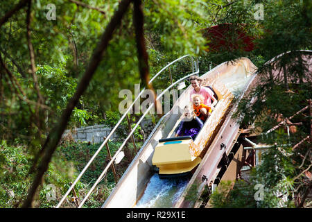 Family with kids on roller coaster in amusement theme park. Children riding high speed water slide attraction in entertainment fun fair during summer  Stock Photo