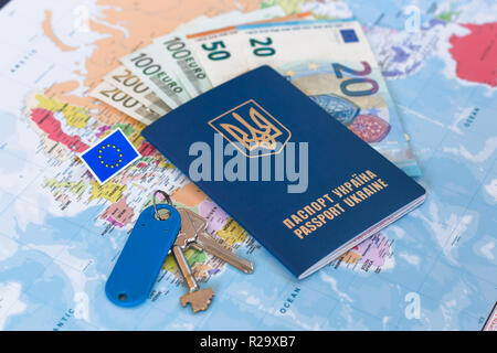 Different euro banknotes inside of Ukrainian travel passport on a world map background. Shallow depth of field, focus on passport and keys.  EU flag m Stock Photo