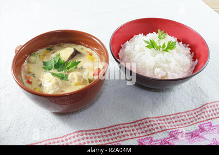 Moqueca of fish and bell peppers, food Brazilian, served with white rice, on a wooden table. Stock Photo