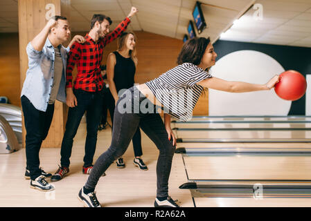 Female bowler on lane, ball throwing in action, strike shot preparation. Bowling alley teams playing the game in club, active leisure Stock Photo