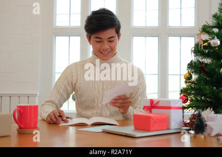 man wearing cream sweater writing christmas letter greeting card ...